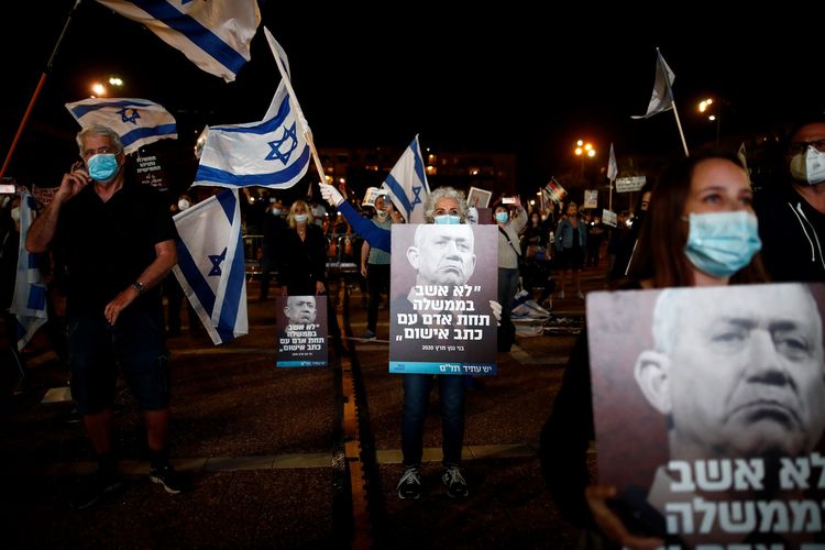 Demonstran Israel memegang poster Benny Gantz ketua Partai Biru dan Putih yang bertuliskan Saya tidak akan duduk di pemerintahan bersama terdakwa kasus pidana. Demonstran tetap mengenakan masker dan mematuhi social distancing saat berunjuk rasa. Foto diambil pada Minggu (19/4/2020).