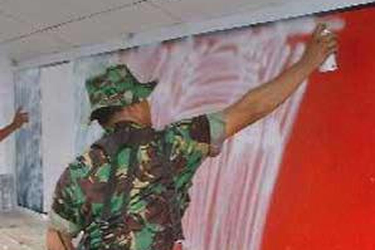 Aparat keamanan dari Tentara Nasional Indonesia saat menghapus bendera Republik Maluku Selatan (RMS) dengan cat semprot di lorong PMI Kuda Mati, Ambon, 3 Mei 2002.