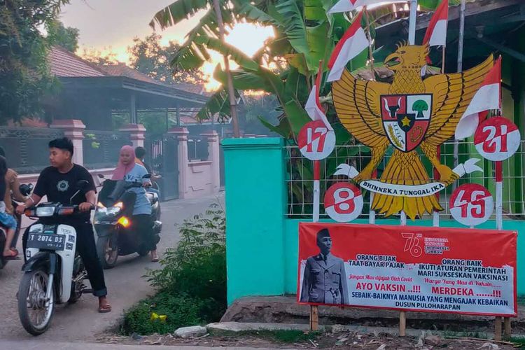 Melalui pernak pernik HUT RI, Pemerintah Desa (Pemdes) Kampungsawah, Kecamatan Jayakerta, Kabupaten Karawang melakukan kampanye ayo vaksin.