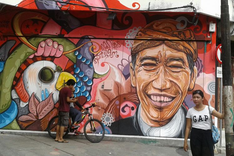 Warga tengah berfoto di sekitar lukisan mural wajah Presiden Joko Widodo (Jokowi) di Koridor Gatot Subroto Solo, Jawa Tengah, Senin (20/11/2017).