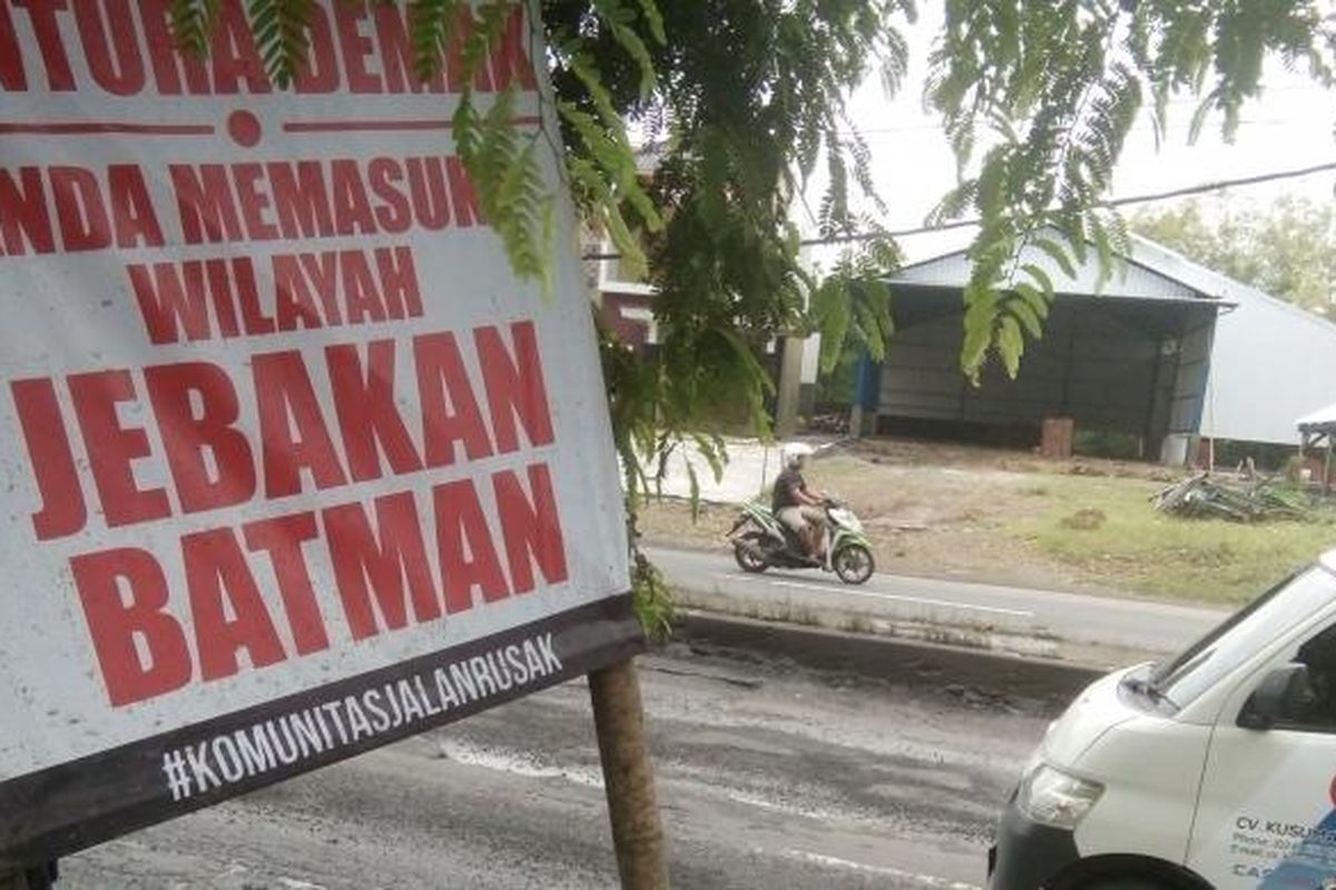 Sebuah kendaraan saat melintasi spanduk bertuliskan sindiran terhadap jalan yang rusak di ruas jalan Pantura Demak, Jawa Tengah, Jumat (10/2/2017).