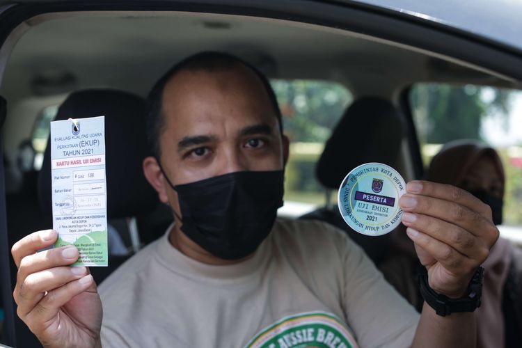 Warga menunjukkan stiker dan kartu lolos uji emisi kendaraan di Depok, Selasa (16/11/2021). Dinas Lingkungan Hidup dan Kebersihan (DLHK) Kota Depok memberikan layanan uji emisi kendaraan roda empat secara gratis selama tiga hari ke depan.