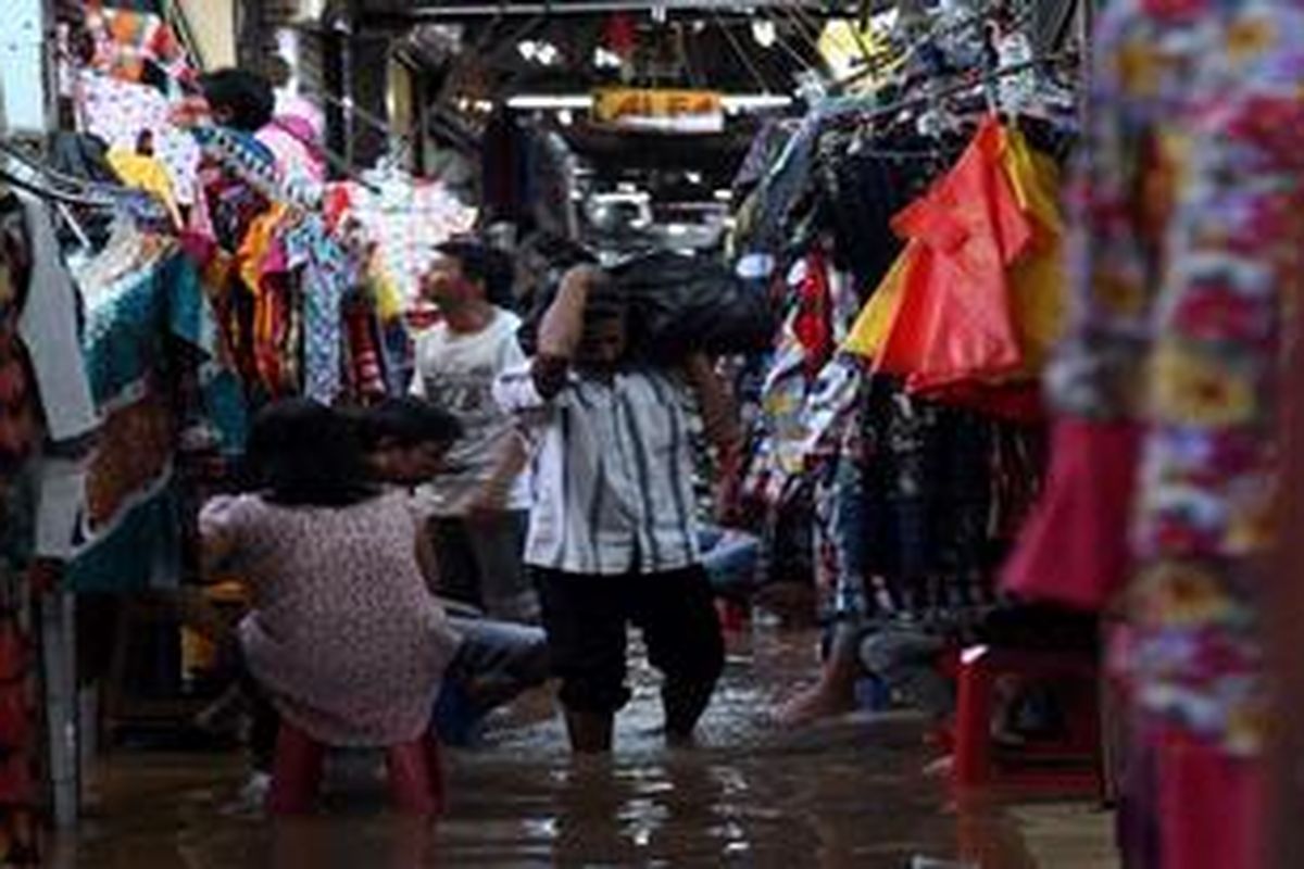 Warga memanggul barang belanjaan saat melintas di air banjir yang menggenangi Pasar Cipulir, Jakarta Selatan, Kamis (18/4/2013). Banjir yang menggenangi pasar itu mem buat sejumlah toko tutup lebih awal karena sepi pembeli.
