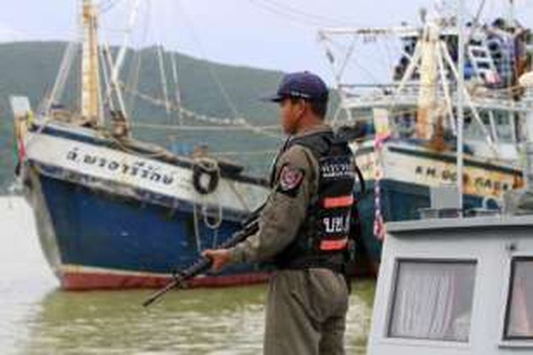 Seorang polisi Thailand berjaga di dekat sebuah kapal ikan yang diduga terlibat perbudakan.