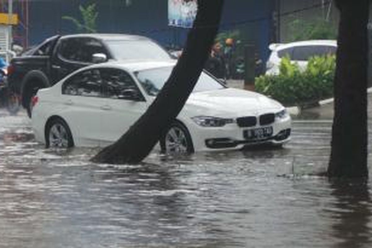 Diduga mogok karena banjir, sedan BMW bernomor polisi B 1920 TAD berwarna putih terjebak di tengah banjir yang menggenangi Jalan Boulevard Barat, Kelapa Gading, Jakarta Utara, Jumat (23/1/2015).