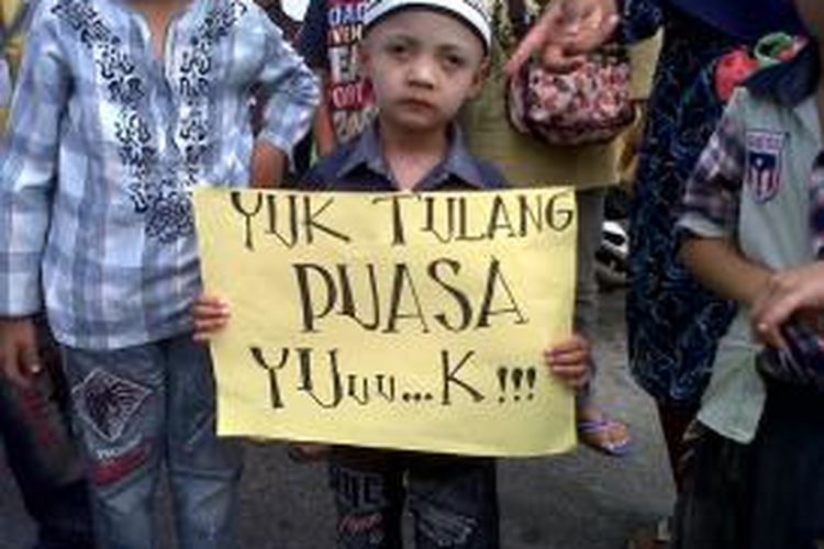 Salah seorang anak saat membawa poster yang isinya mengajak warga agar berpuasa selama bulan suci Ramadhan, saat ratusan anak-anak pengajian masjid Rahmat, Jalan Singosari, Pematangsiantar, Sumatera Utara gelar pawai Ta'ruf, Minggu (7/7/2013).