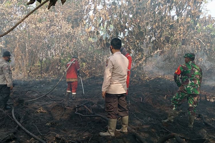 Petugas kepolisian, TNI dan Manggala Agni saat berupaya memadamkan api karhutla di Jalan Perwira, Desa Rimbo Panjang, Kecamatan Tambang, Kabupaten Kampar, Riau, Jumat (6/10/2023).