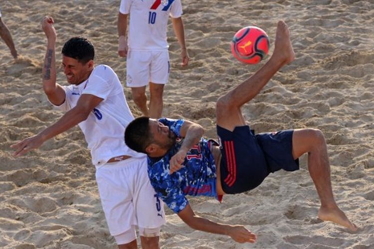 Masanori Okuyama (kanan) mendapat hadangan dari Gustavo Arnaldo Benitez (kiri) dalam laga Piala Interkonental sepak bola pantai antara Jepang dan Paraguay di Dubai, 4 November 2021.