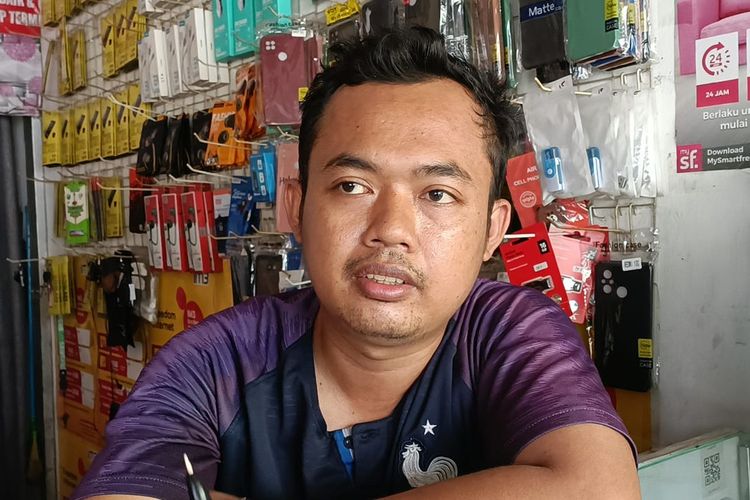 Rori (32) saat ditemui di konter hp miliknya di Jalan Raya Telaga Asih, Kampung Citra, Cikarang Barat, Kamis (27/7/2023). Ia sendiri menjadi korban penipuan dengan modus tukar uang receh yang ternyata berisi tanah.