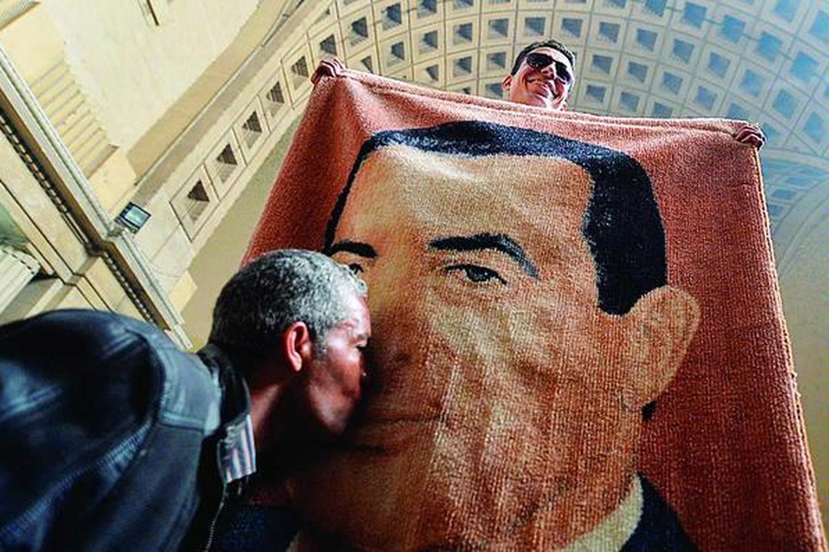 Warga Mesir mencium karpet bergambar wajah mantan Presiden Hosni Mubarak di Kairo, Minggu (13/1). Pendukung Mubarak menyambut gembira keputusan Pengadilan Tinggi Mesir untuk menyidangkan kembali Mubarak dan sejumlah kroninya.