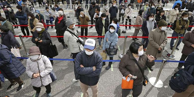 Warga dengan masker pelindung menjaga dari penularan virus COVID-19, mengantre secara berjarak untuk menyaksikan api Olimpiade saat tur Reli Api Olimpiade Tokyo 2020 di Fukushima, Jepang, Selasa (24/3/2020).