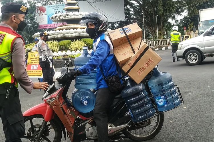 Seorang petugas kepolisian menanyakan tujuan kepada pengendara motor berplat nomor genap di persimpangan Tugu Adipura, Sukabumi, Jawa Barat, Jumat (13/8/2021).