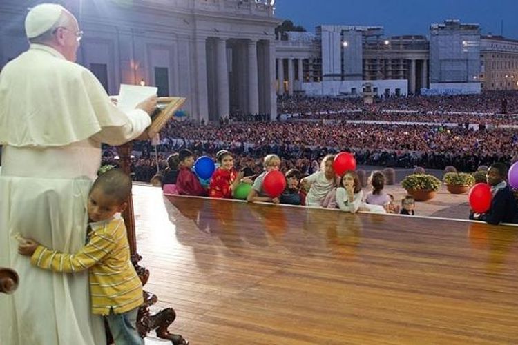 Seorang anak berlari ke panggung dan memeluk Paus Fransiskus saat Pemimpin Tertinggi Gereja Katolik Sedunia itu berkhotbah di depan kerumunan massa di alun-alun St Petrus di Vatican City, beberapa waktu lalu. (Dokumentasi)