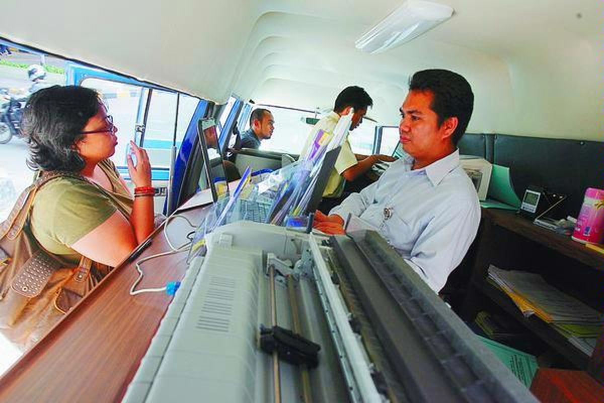 Warga menunggu pembuatan kartu Nomor Pokok Wajib Pajak (NPWP) melalui mobil keliling yang juga melayani pelaporan Surat Pemberitahuan (SPT) tahunan pajak di ITC Kuningan, Jakarta Selatan, Rabu (26/3). Mobil yang dioperasikan Ditjen Pajak itu bertujuan untuk mempermudah masyarakat mengurus pajak.  