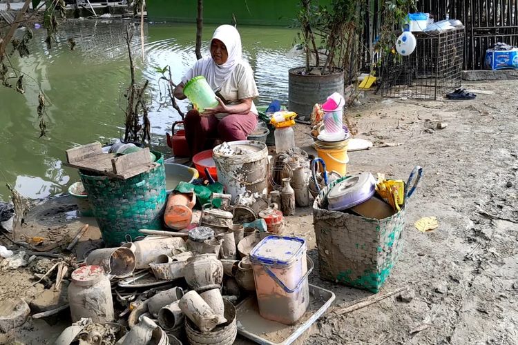 Salah satu warga Desa Karanganyar mencuci perabotan rumah pasca banjir surut, Minggu (24/3/2024). (KOMPAS.COM/NUR ZAIDI).