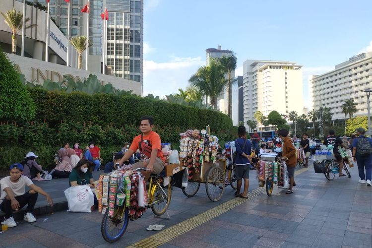 Warga Jakarta yang berjalan-jalan dan menikmati Bundaran HI sambil berfoto-foto. Serta pedagang yang menjual makanan atau minuman di depan trotoar Plaza Indonesia. 