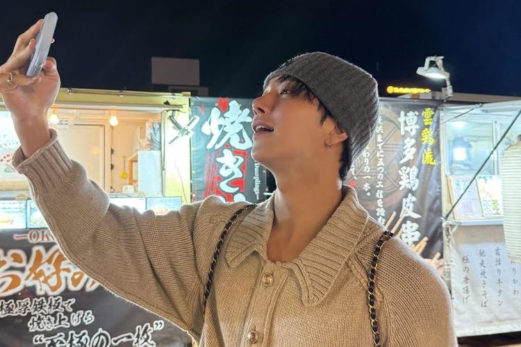 Joshua Hong mengenakan kardigan oversized dan beanie rajut.
