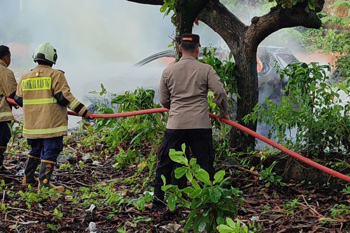 Kepala Kepolisian Sektor (Kapolsek) Kuta Selatan, Kompol I Gusti Ngurah Yudistira bersama petugas Damkar Kabupaten Badung saat berupaya memadamkan api dalam peristiwa kebakaran Mobil Daihatsu Xenia putih bernomor polisi DK 1097 UV  di Nusa Dua, Kecamatan Kuta Selatan, Kabupaten Badung, Bali, Selasa (21/1/2025).