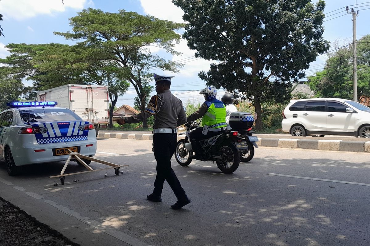 Anggota Satlantas Polres Karawang sedang menyisir ranjau paku di Jalan Lingkar Luar Karawang, Sabtu (15/4/2023).