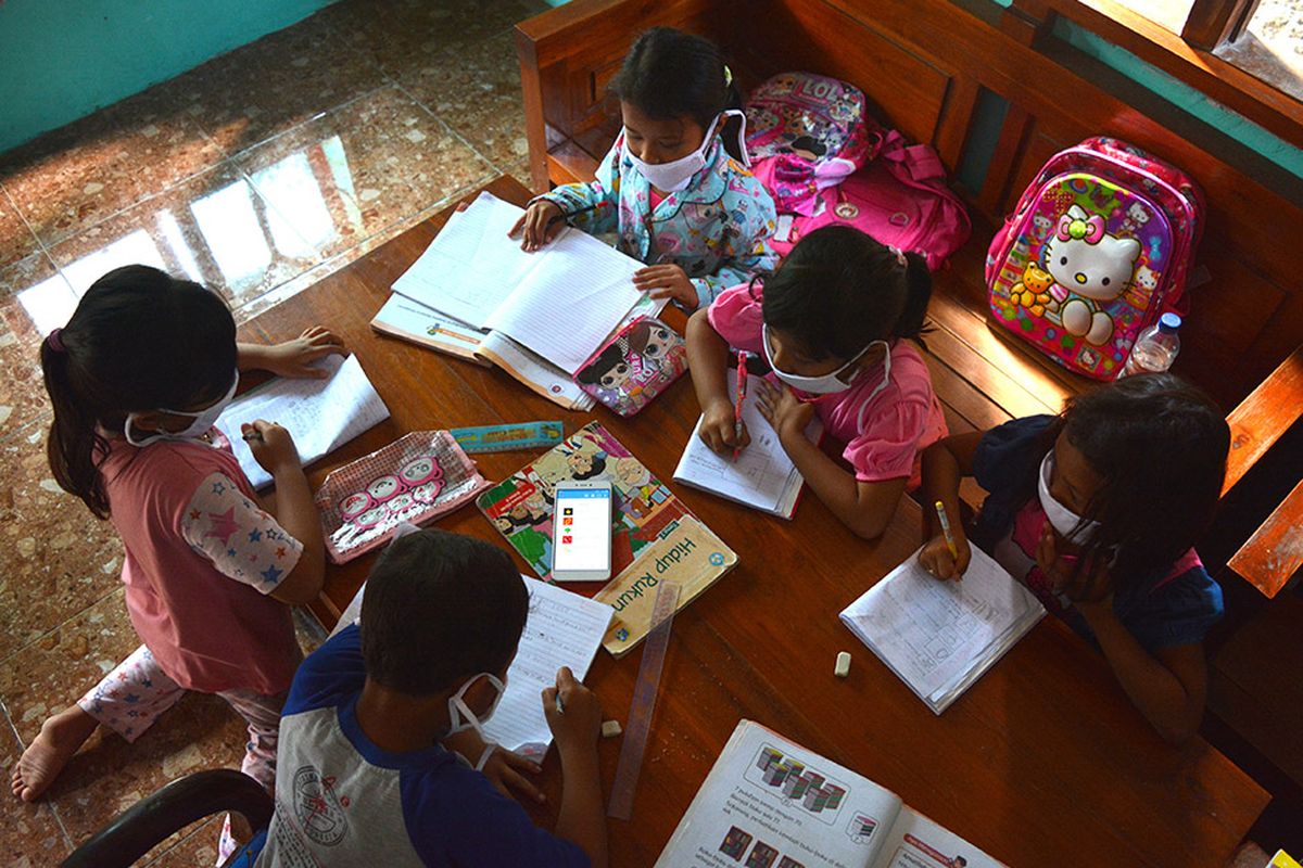 Sejumlah siswa SDN Marmoyo mengerjakan tugas dengan berkelompok menggunakan gawai secara bergantian di rumah warga Desa Marmoyo, Kecamatan Kabuh, Kabupaten Jombang, Jawa Timur, Rabu (22/7/2020). Banyaknya siswa yang tidak punya gawai dan akses jaringan internet menjadi kendala utama pelaksanaan pembelajaran jarak jauh bagi pelajar yang tinggal serta sekolah di daerah pelosok Kabupaten Jombang, sehingga mereka harus mengerjakan tugas secara berkelompok dan menumpang di rumah warga yang bisa mengakses jaringan internet.