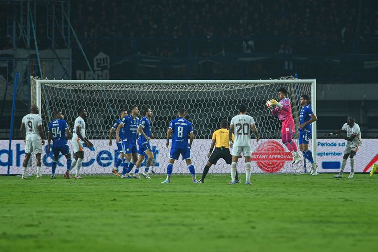 Aksi penjaga gawang muda Persib Bandung Fitrah Maulana dalam memotong bola crossing Borneo FC Samarinda dalam laga debutnya di Super League 2025-2026, Jumat (5/12/2025) di Gelora Bandung Lautan Api (GBLA). 