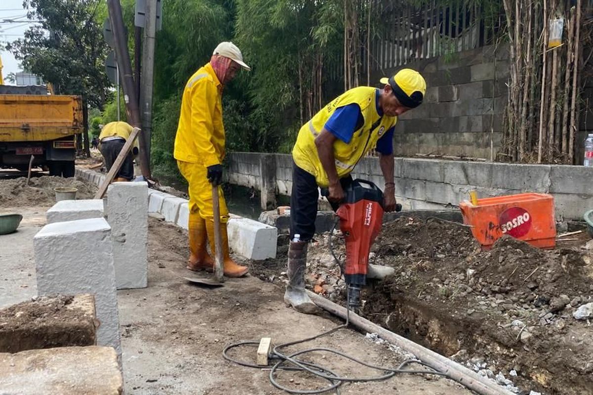 Satpel Bina Marga Kecamatan Kelapa Gading, Jakarta Utara memperbaiki kanstip yang sudah rata dengan jalan dan membuat tali air untuk mencegah genangan air saat hujan, Selasa (10/5/2022)..