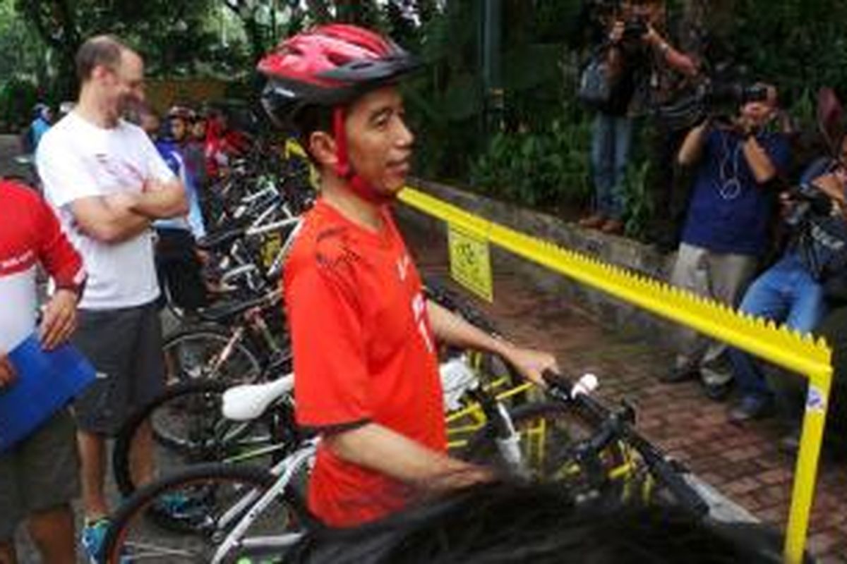 Gubernur DKI Jakarta Joko Widodo mengenakan konstum Persija dan bersepeda menuju Balaikota, Jumat (3/1/2014). 