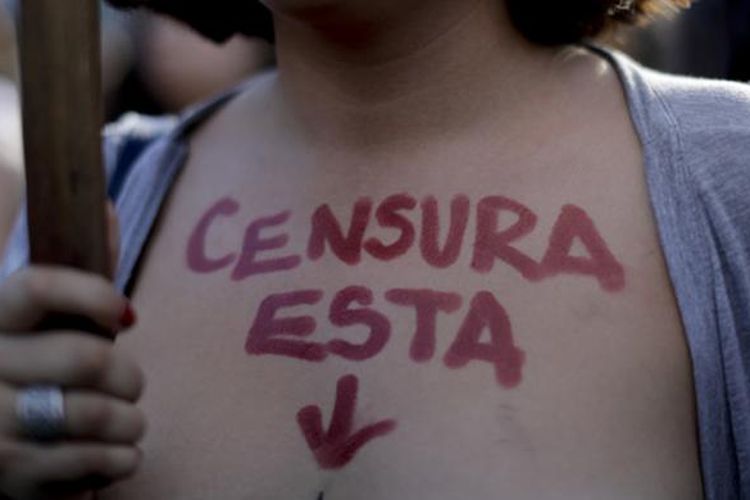 Seorang wanita tanpa penutup dada yang ambil bagian dalam aksi unjuk rasa di Buenos Aires, Argentina, Rabu WIB (8/2/2017), menulisi dadanya dengan kata-kata dalam bahasa Spanyol, yang artinya 