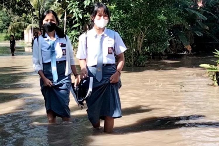 Siswi SMA 4 Luwu mencoba berjalan untuk sampai di sekolahnya namun tak mampu akibat jalan yang dilalui terendma banjir yang bervariasi antara 60 hingga 90 sentimeter, Senin (03/01/2022).