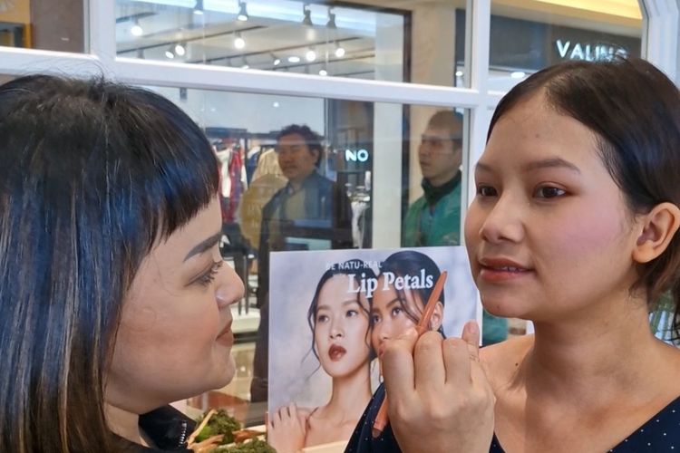 Founder & CMO BLP Beauty Lizzie Parra (kiri) saat mengaplikasikan Lip Petals pada salah seorang pengunjung di gerai BLP Beauty, PIM, Jakarta Selatan, Selasa (5/3/2024).