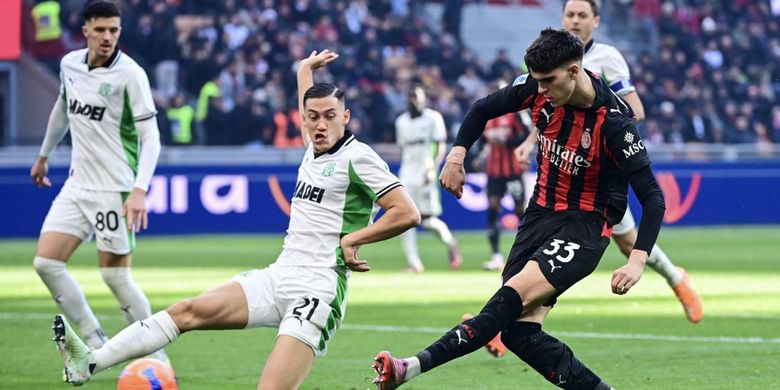 Jay Idzes (kiri) mencoba membendung tembakan Davide Bartesaghi (kanan) dalam laga Liga Italia 2025-2026 AC Milan vs Sassuolo di Stadion San Siro, 14 Desember 2025. (Photo by Piero CRUCIATTI / AFP)