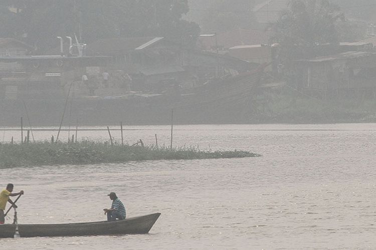 Ojek perahu melintas di sungai Siak yang terpapar kabut asap dampak dari kebakaran lahan, di Pekanbaru, Riau, Sabtu (7/9/2019). Dinas Kesehatan setempat menghimbau kepada seluruh masyarakat agar selalu mengenakan masker pelindung pernapasan di saat beraktivitas di luar ruangan.