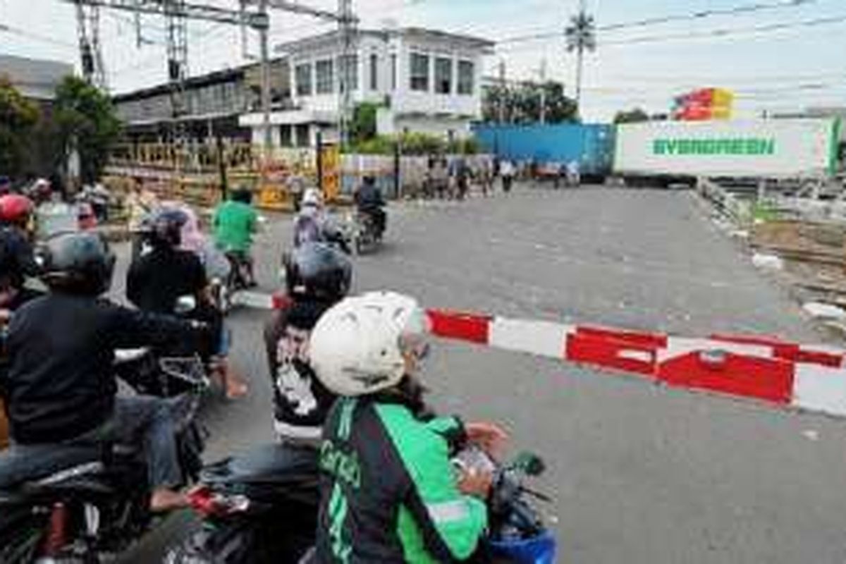 Pengendara sepeda motor berhenti di pintu pelintasan kereta api sebidang Pasar Senen, Jakarta Pusat, Selasa (27/9). Uji coba penutupan pelintasan kereta api sebidang di Pasar Senen mulai diberlakukan pada 1 Oktober. 