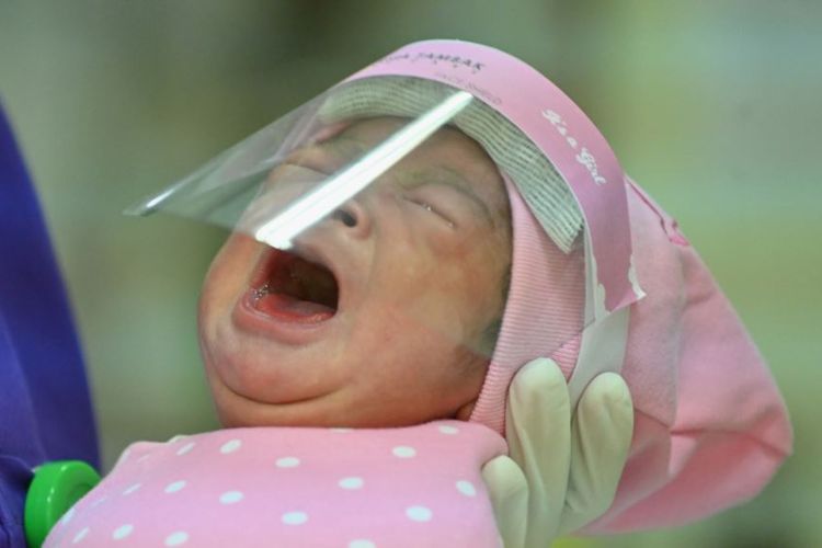 Seorang perawat menggendong bayi yang baru lahir yang dilindungi dengan pelindung wajah di tengah wabah virus corona, sebagai ilustrasi.