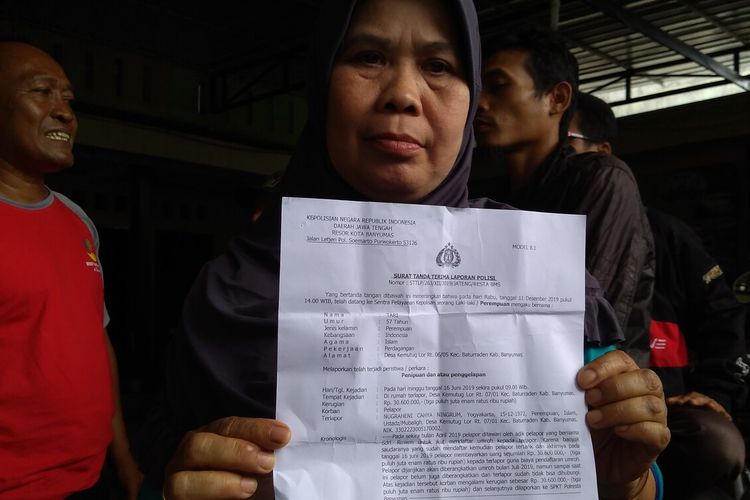 Tari (50) menunjukkan surat laporan polisi saat mendatangi sebuah pondok pesantren sekaligus kantor biro perjalanan umrah di Desa Kemutug Lor, Kecamatan Baturraden, Kabupaten Banyumas, Jawa Tengah, Minggu (15/12/2019).