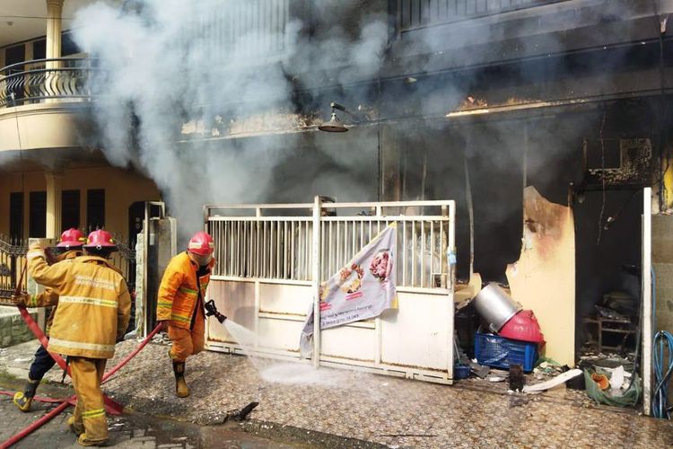 Petugas Damkarla Gresik sedang berupaya memadamkan api yang membakar rumah Sumiati di perumahan GKB, Gresik, Jawa Timur, Senin (19/12/2022).