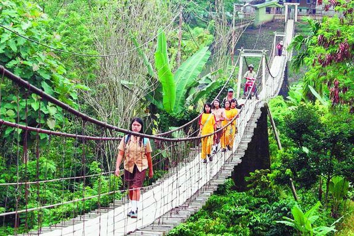 Warga Desa Pagar Batu, Kabupaten Lahat, Sumatera Selatan, melewati jembatan gantung yang melintasi sungai di daerah tersebut, Sabtu (23/2).  