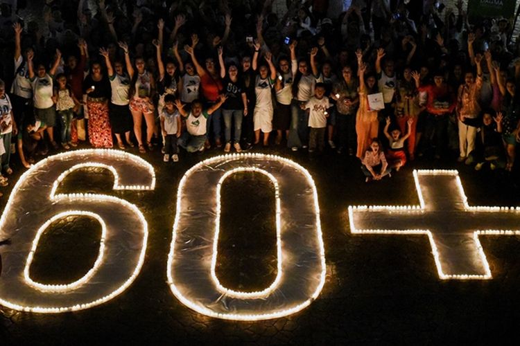 Masyarakat menyalakan lilin dan membentuk simbol 60+ dalam  kampanye lingkungan Earth Hour di Cali, Kolombia, Sabtu (24/3/2018). (AFP/Luis Robayo)

