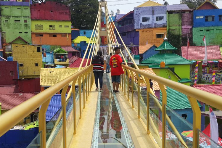 Sejumlah wisatawan saat melintas di jembatan kaca yang menghubungkan Kampung Warna - warni dan Kampung Tridi di Kota Malang, Jawa Timur, Selasa (10/10/2017)