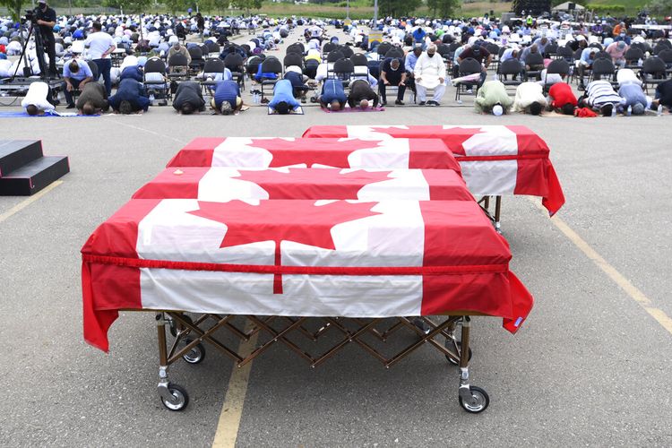 Para pelayat berdoa saat peti mati terbungkus bendera Kanada berbaris di pemakaman untuk empat anggota keluarga Muslim yang tewas dalam serangan kendaraan mematikan, di Islamic Center of Southwest Ontario di London, Ontario, pada Sabtu, 12 Juni 2021. 