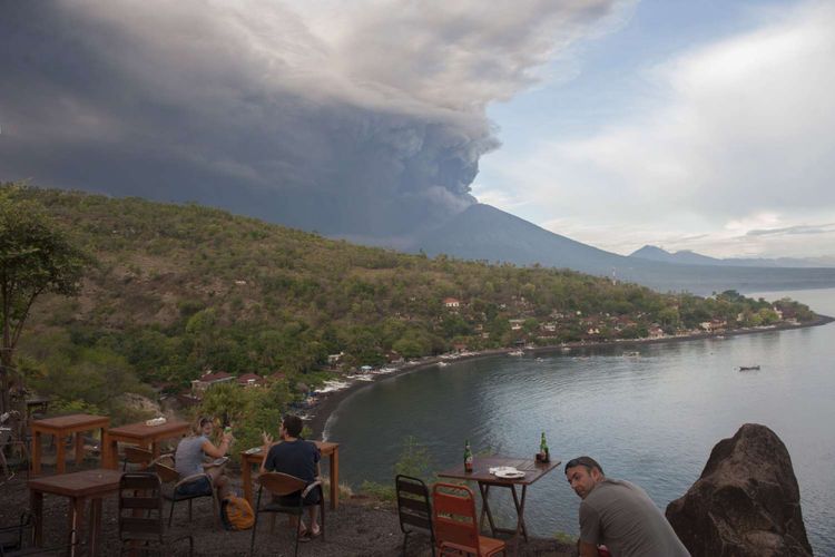 Sejumlah wisatawan menyaksikan letusan Gunung Agung dari Pantai Jemeluk, Karangasem, Bali, Minggu (26/11/2017). Pusat Vulkanologi dan Mitigasi Bencana Geologi menyatakan telah terjadi letusan freatik kedua pada pukul 17.20 Wita yang disusul dengan semburan asap dan abu vulkanis hingga ketinggian 3.000 meter. 