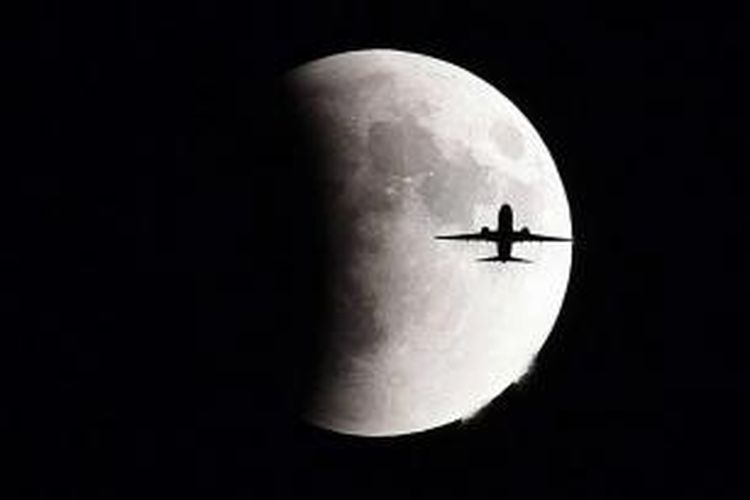 Pesawat terbang dengan latar belakang bulan purnama (supermoon) yang sedang mengalami proses gerhana, Minggu (27/9/2015), di Jenewa, Swiss.