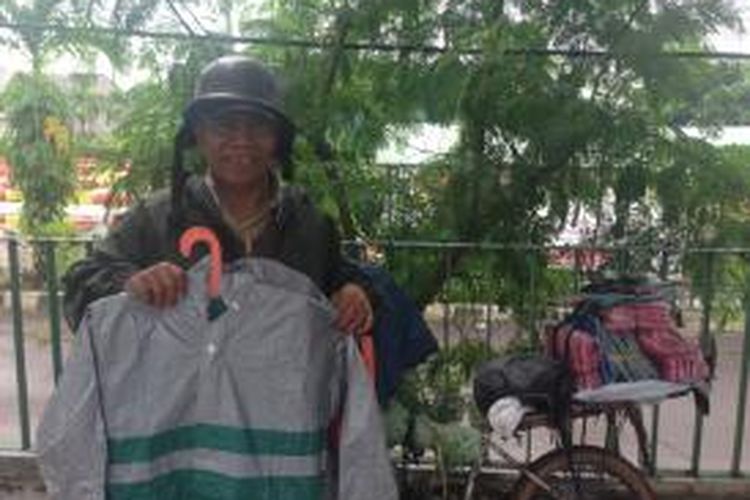 Taseli (50) seorang penjaja jas hujan di Tendean, Jakarta Selatan, sedang memamerkan barang daganganya kepada Kompas.com, Rabu (14/1/2015). Dalam sehari Taseli mampu menjual 40 potong jas hujan dengan kisaran harga Rp. 55.000. 