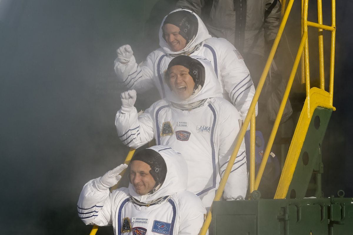 Members of the International Space Station (ISS) expedition 53/54, NASA astronaut Scott Tingle (top), Roscosmos cosmonaut Anton Shkaplerov (bottom) and Norishige Kanai of the Japan Aerospace Exploration Agency (C) (JAXA) wave as they climb a ladder to the rocket at the Russian-leased Baikonur Cosmodrome in Kazakhstan early on December 17, 2017.
NASA astronaut Scott Tingle and crewmates Anton Shkaplerov of the Russian space agency Roscosmos and Norishege Kanai of the Japan Aerospace Exploration Agency were expected to lift off in the Soyuz MS-07 spacecraft from the Baikonur Cosmodrome. / AFP PHOTO / Shamil ZHUMATOV