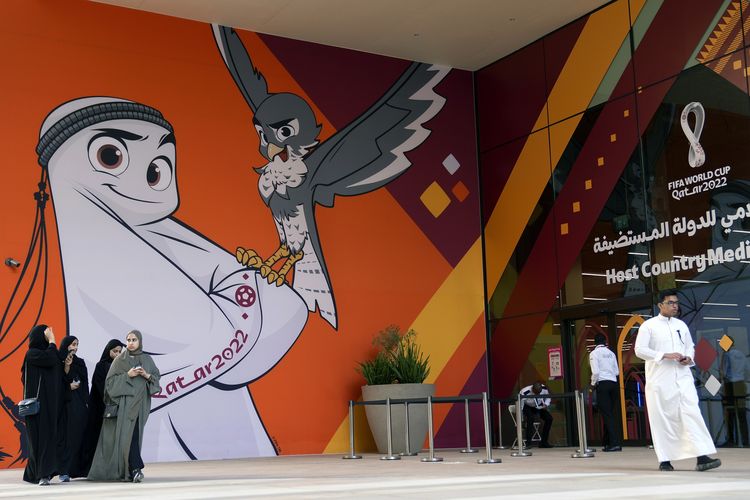 Orang-orang berjalan di depan gambar maskot Piala Dunia 2022 Qatar, La'eeb, di Doha pada 12 November 2022.