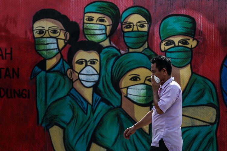 Warga menggunakan masker saat melintas di depan mural tentang pandemi virus corona atau COVID-19 di Jalan Raya Jakarta-Bogor, Depok, Jawa Barat, Selasa (7/4/2020). Mural tersebut ditujukan sebagai bentuk dukungan kepada tenaga medis yang menjadi garda terdepan dalam menghadapi COVID-19 di Indonesia.