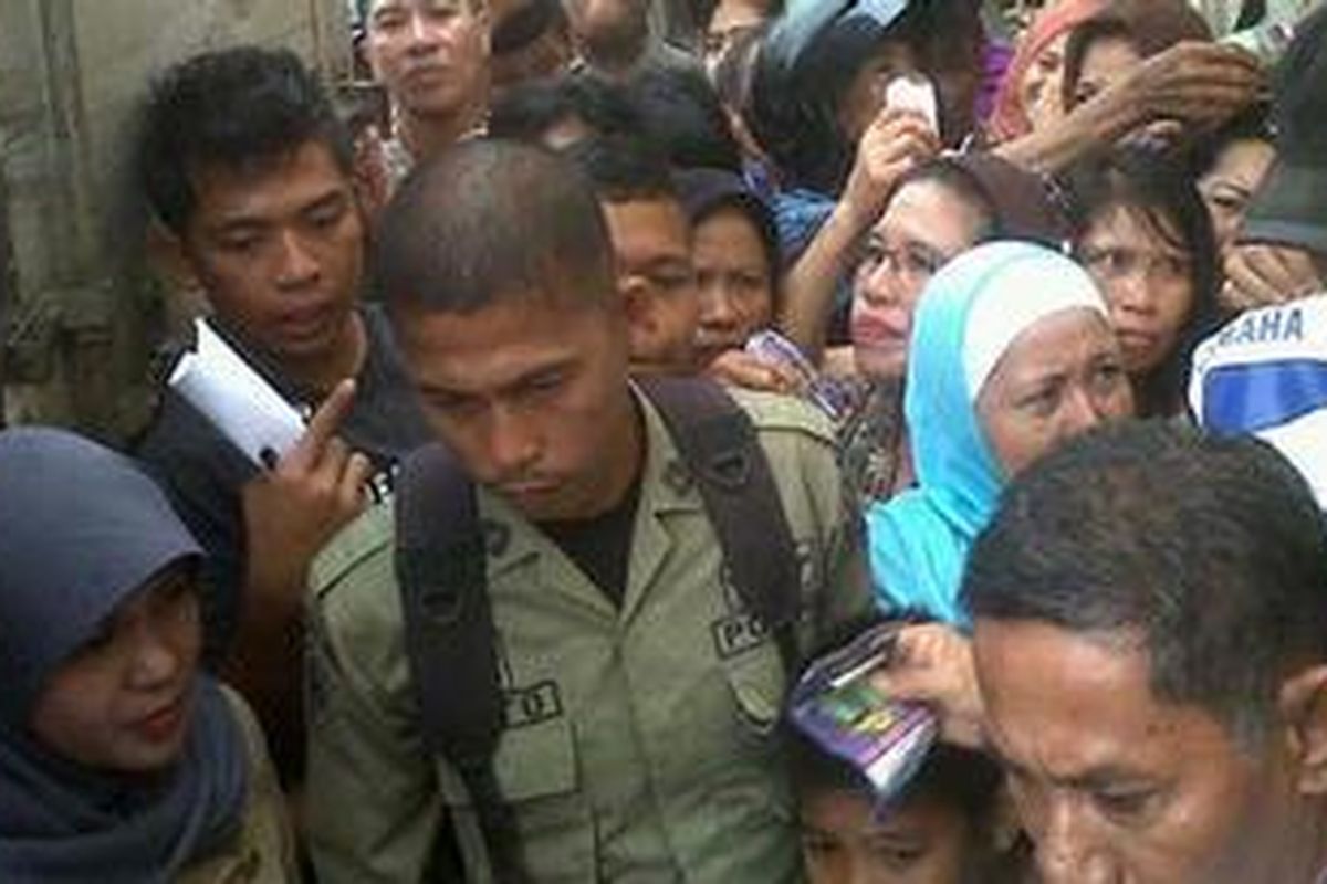 Seorang Aparat Polisi Pamong Praja (Pol-PP) di Kabupaten Bone Sulawesi Selatan berusaha menenangkan warga yang terlibat saling dorong saat pembagian kupon pembelian pasar murah, Selasa, (17/7/2012).