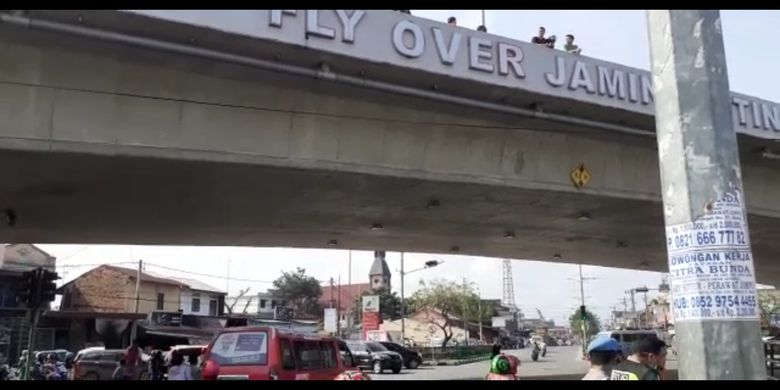 Tangkapan layar video yang merekam sejumlah orang berdiri di atas jembatan layang (fly over) di Jalan Jamin Ginting Medan, Kamis siang (30/1/2020). Pada pagi tadi, seorang pria berjaket dan mengenakan seragam polisi diduga melompat dari atas jembatan dan membuat heboh warga yang melintas di jalan tersebut.