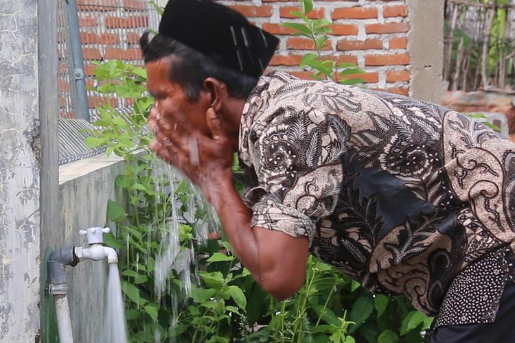 warga Dusun Pelita, Gampong Meunasah Mon, Krueng Raya, Kabupaten Aceh Besar sedang berwudhu di pekarangan rumah, selama ada bantuan sumur bor dari pertamina mereka tidak perlu lagi harus ke sungai untuk kebutuhan air sehari hari.