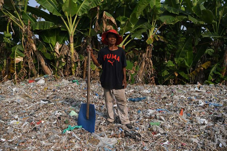 Foto dirilis Selasa (6/8/2019), menunjukkan seorang warga berpose di atas tumpukan sampah plastik impor di Desa Bangun di Mojokerto, Jawa Timur. Indonesia diperkirakan setiap harinya menerima sedikitnya 300 kontainer sampah yang sebagian besar menuju ke Jawa Timur, diduga dampak kebijakan China yang menghentikan impor sampah plastik dari sejumlah negara di Uni Eropa dan Amerika.